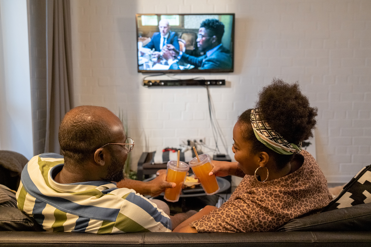 black couple watching tv on couch