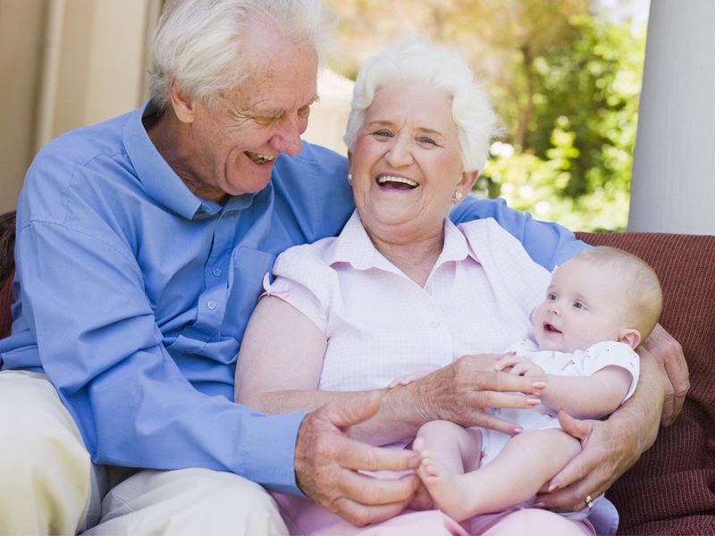 elderly couple grandparents with baby smiling